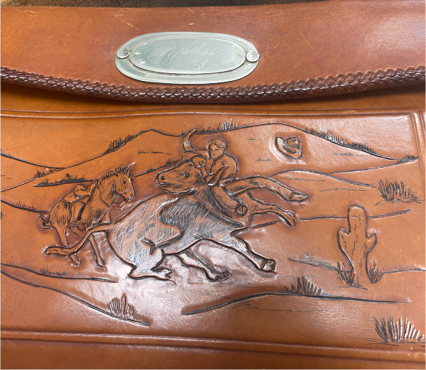Brown leather bag with embossed design of a rider on horseback and landscape.