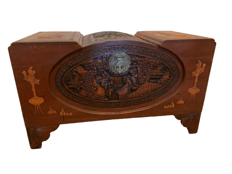 Wooden jewelry box with intricate designs on a wooden floor.